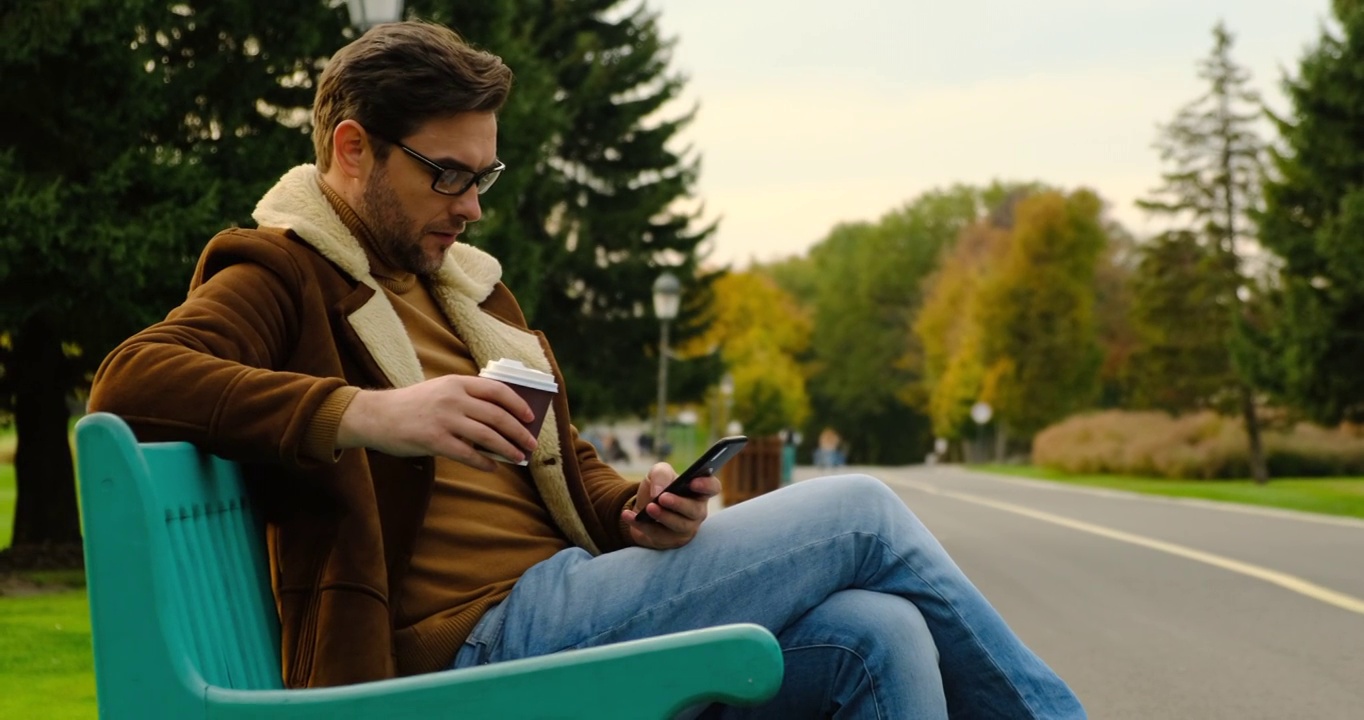 加拿大城市公园，商人在公园长椅上用手机喝咖啡