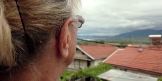 旁边的老妇人，奶奶，站在阳台上遥望远方，想着过去和回忆