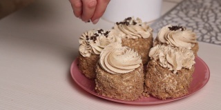 一位女士用奶油和饼干屑做海绵蛋糕。用奶油和巧克力末装饰。特写镜头。