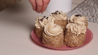 一位女士用奶油和饼干屑做海绵蛋糕。用奶油和巧克力末装饰。特写镜头。视频素材模板下载