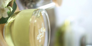 一滴茶落入一杯茉莉花绿茶。新鲜的茉莉花在杯子里和附近