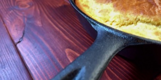 棕色的桌子上放着用黑色铸铁煎锅烤的玉米面包