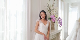 4K美丽的亚洲女性新娘选择试穿白色婚纱在试衣间。