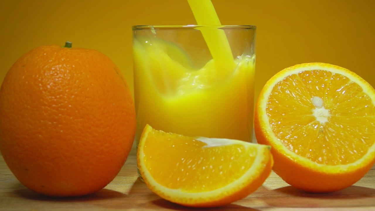 新鲜甜橙汁倒在一个玻璃杯里，旁边是成熟的橙子