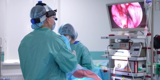 进行手术的专业外科医生。穿着特殊衣服和技术设备的医生看着显示手术区域的屏幕。
