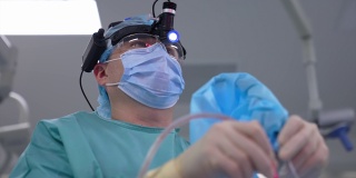 外科医生在诊所为病人手术。医生穿着医用制服和口罩，使用无菌器械和医用管进行手术。