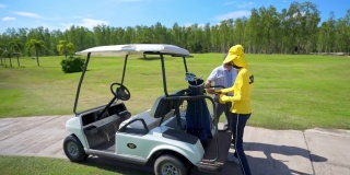 4K亚洲高级男子驾驶高尔夫球车在高尔夫球场与女球童高尔夫球草地