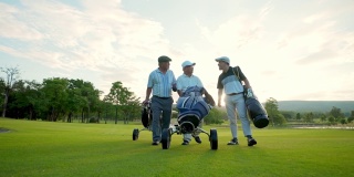 4K集团亚洲商人和高级CEO拿着高尔夫球袋在夏日夕阳下一起走在高尔夫球道上