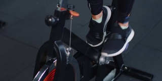 近距离的运动妇女旋转锻炼锻炼在固定自行车机器自行车，室内