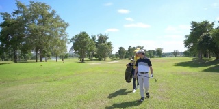 4K亚洲男子高尔夫球手与女球童在高尔夫球场上行走