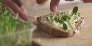 做一个有营养的三明治。一片全麦面包和乳清干酪放在竹制面包板上