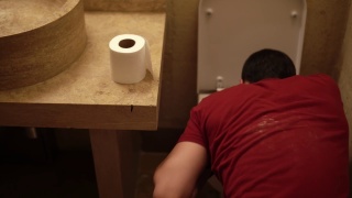 男子坐在浴室的地板上呕吐，然后擦嘴的特写镜头视频素材模板下载