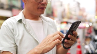 泰国曼谷夜市，一名4K亚洲男子在使用智能手机旅行视频素材模板下载