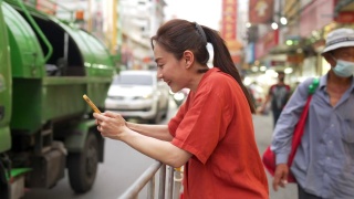 在泰国曼谷的夜市，一名4K亚洲妇女在使用智能手机旅行视频素材模板下载