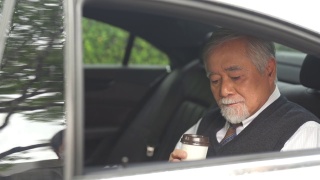 4K亚洲资深商人坐在车后座喝着热咖啡视频素材模板下载