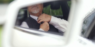 坐在车里的4K亚洲高级商人在开车前整理他的衬衫和领带。