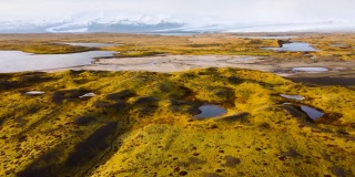 空中飞行在冰岛上空，从鸟瞰图上可以看到神奇的火山地貌，绿色的苔藓和蓝绿色的湖泊。美丽而原始的自然