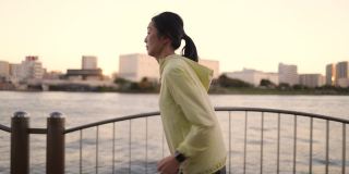 日落时分的东京，一名女子在河边奔跑