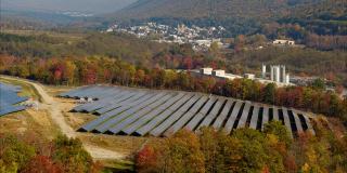 宾夕法尼亚州阿巴拉契亚山脉的大型太阳能农场，在一个多彩的秋天。空中视频与复杂的平移前向摄像机运动。