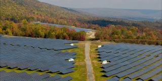 宾夕法尼亚州阿巴拉契亚山脉的大型太阳能农场，在一个多彩的秋天。空中视频与前进和上升，倾斜向下的相机运动。