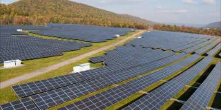 宾夕法尼亚州阿巴拉契亚山脉的大型太阳能农场，在一个多彩的秋天。空中视频与前进和上升的摄像机运动。