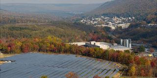 宾夕法尼亚州阿巴拉契亚山脉的大型太阳能农场，在一个多彩的秋天。空中视频与反向摄像机运动。