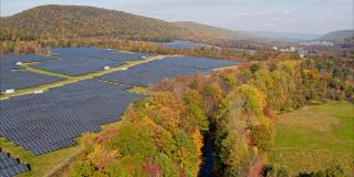 宾夕法尼亚州阿巴拉契亚山脉的大型太阳能农场，在一个多彩的秋天。空中视频与平移相机运动。