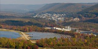 宾夕法尼亚州阿巴拉契亚山脉的大型太阳能农场，在一个多彩的秋天。空中视频与向后平移相机运动。