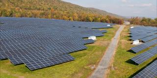 宾夕法尼亚州阿巴拉契亚山脉的大型太阳能农场，在一个多彩的秋天。空中视频与前进和上升相机运动与多莉缩放效果。