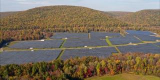 宾夕法尼亚州阿巴拉契亚山脉的大型太阳能农场，在一个多彩的秋天。空中视频与平移相机运动。