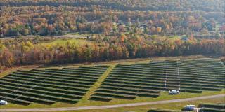 宾夕法尼亚州阿巴拉契亚山脉的大型太阳能农场，在一个多彩的秋天。加速航拍视频与平移和宽轨道摄像机运动。