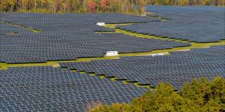 宾夕法尼亚州阿巴拉契亚山脉的大型太阳能农场，在一个多彩的秋天。空中视频与平移和倾斜的相机运动。
