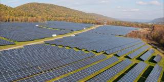 宾夕法尼亚州阿巴拉契亚山脉的大型太阳能农场，在一个多彩的秋天。加速航拍视频与复杂的电影向前和下降，然后上升相机运动。
