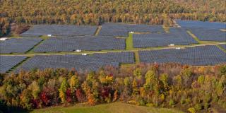 宾夕法尼亚州阿巴拉契亚山脉的大型太阳能农场，在一个多彩的秋天。空中视频与平移和倾斜的相机运动。