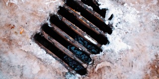 带有生锈格栅的街道排水管道在冬季从冰雪中收集水