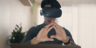 亚洲男人在家带着VR眼镜工作。