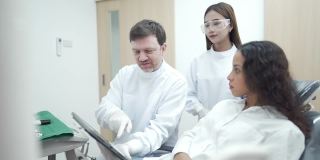 4K男性牙医向女性患者解释牙齿x光图像