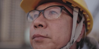 这位亚洲高级工程师用手拿着眼镜，晚上在电站工作