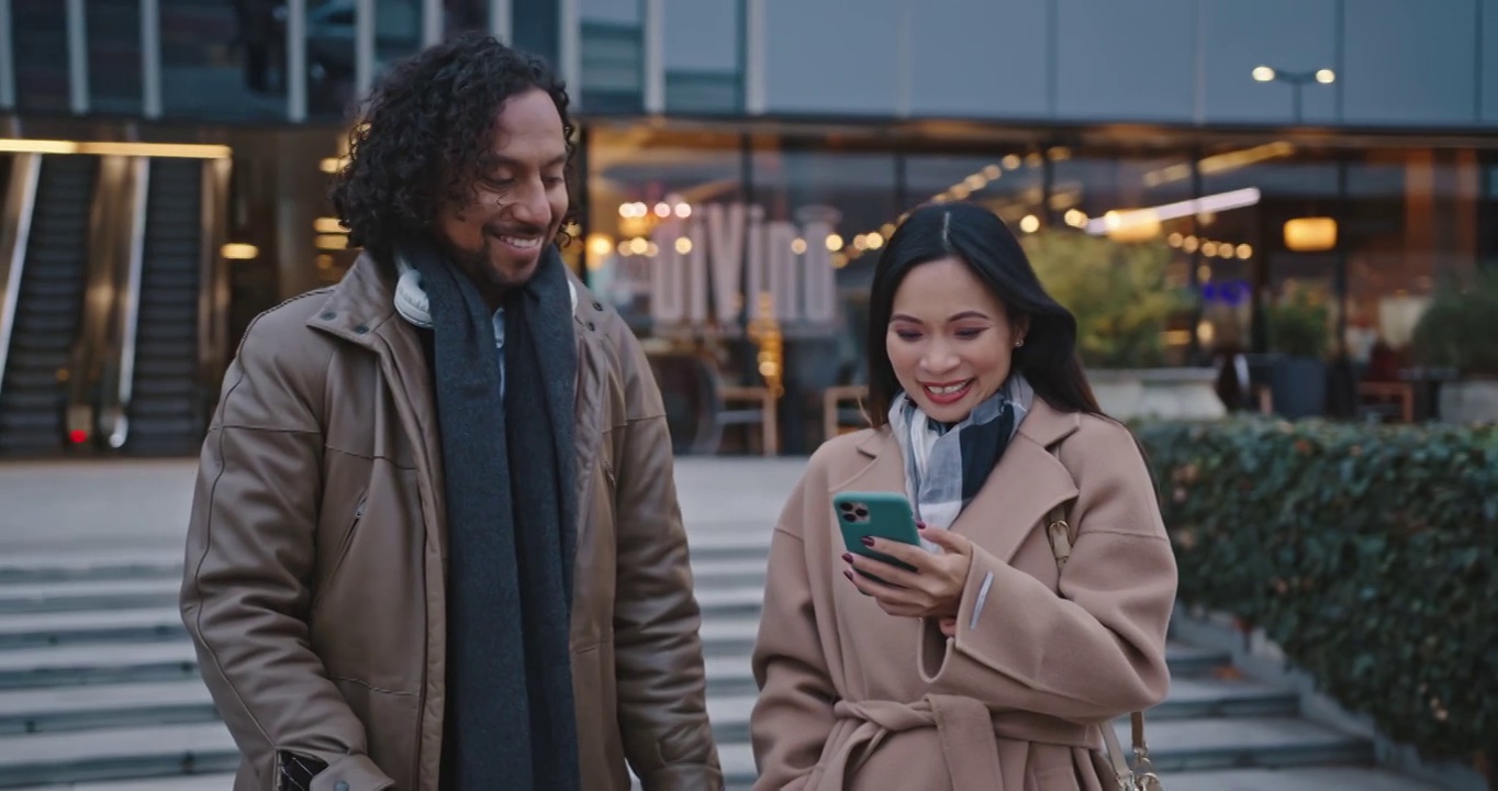 一对拉美裔和亚裔夫妇在商场前用智能手机