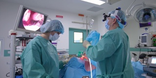 外科医生和他的助手正在进行手术。专业医生通过显示器查看病人的鼻子内部情况。