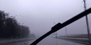 缓慢的运动。在阴雨天行驶的道路上，雨点冲刷着汽车的雨刷