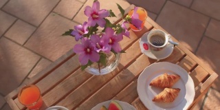 简单的早餐包括在酒店的桌子上的水果、羊角面包和饮料。