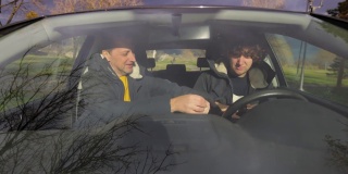 一个中年白人驾驶教练，正在学习他的年轻男学生如何开车