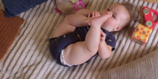 六个月大的婴儿把脚放进嘴里。良好的肌肉张力，屈曲连枷四肢。