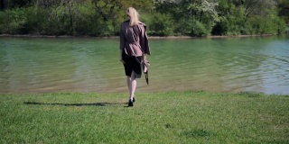 初春，一个苗条的女孩在公园的湖边散步