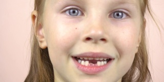 一个小女孩的脸部特写，她露出了掉下来的乳牙，做鬼脸。