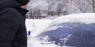 冬天，戴着黑色皮手套的司机用刷子擦车窗上的雪。