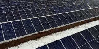 在一个阴天的冬天，数以百计的太阳能电池板排成一排。