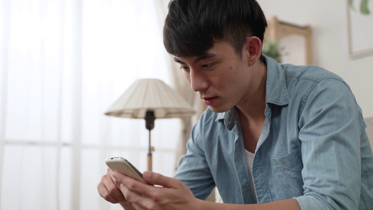 (特写)一名台湾男性在家里用手机阅读一则令人惊讶的网络新闻时，嘴巴张得大大的在手机屏幕上滚动。