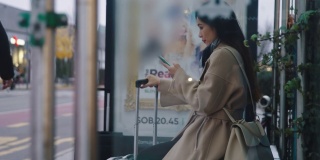 LS亚洲女性在公交车站等车时使用智能手机